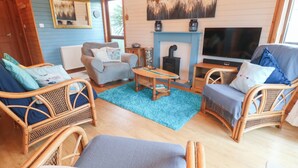 A cozy living room with wicker furniture, a fireplace, and a television. - Lamorna (Penzance)