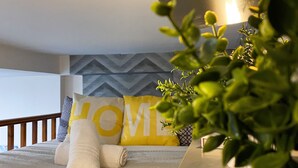A neatly arranged bedroom with a bed, pillows, a potted plant, and a wall with a geometric pattern. - Modern Studios Malvern Road  (London)