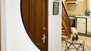 A circular mirror reflecting a kitchen with a wooden door, a staircase, and a dining area. - Modern Studios Malvern Road  (London)