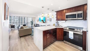 A modern kitchen with a central island, stainless steel appliances, and wooden cabinets. - Ocean & marina view w/ steps to Waikiki Beach (Honolulu)