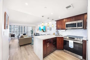 A modern kitchen with a central island, stainless steel appliances, and wooden cabinets. - Ocean & marina view w/ steps to Waikiki Beach (Honolulu)