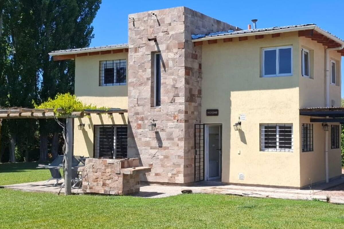 A two-story house with a stone facade, a covered patio, and a small garden area.