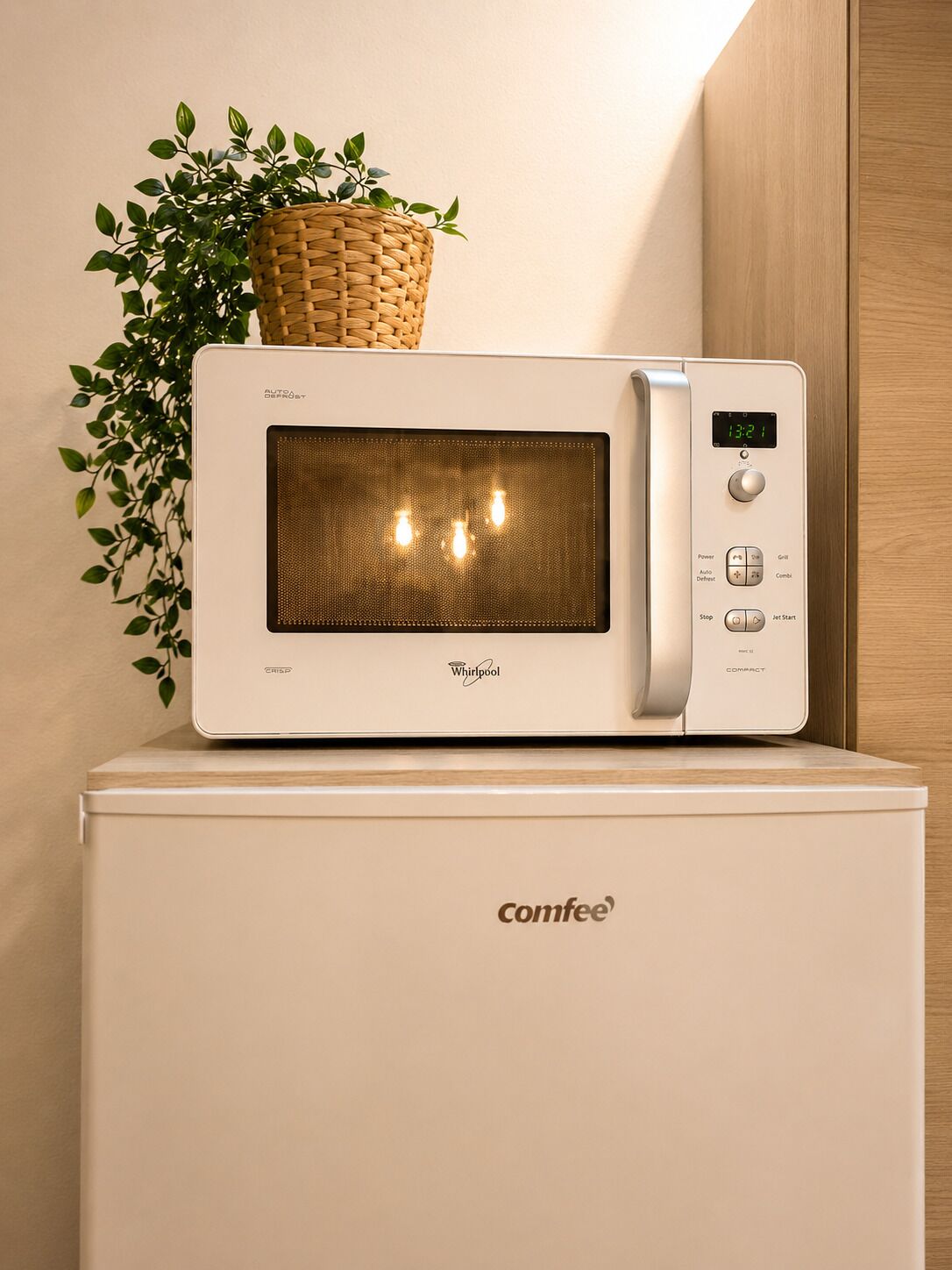 Fornet microones compact amb pantalla digital, damunt d'un frigorífic blanc.