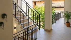 A staircase with black railings leading to a covered outdoor area with tiled flooring and potted plants. - Giulio Collio Suite House (Cormons)