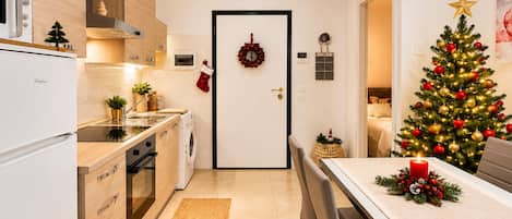 Een moderne keuken met een eethoek, een kerstboom en feestelijke decoraties.