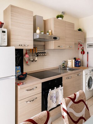 A modern kitchen with wooden cabinets, a built-in oven, a washing machine, and a sink.
