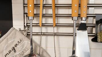 A kitchen with a hanging rack holding three wooden-handled utensils and two metal kitchen tools.