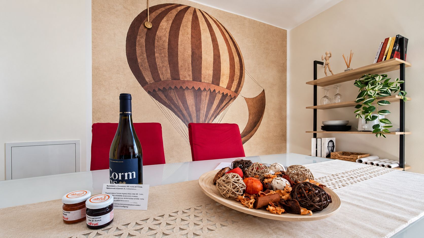 A dining table with a bottle of Corm wine, a plate of assorted food items, and a decorative wall mural.