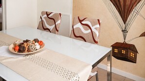 A dining area with a white table, patterned cushions, a clock, and a wall mural of a hot air balloon. - Giulio Collio Suite House (Cormons)