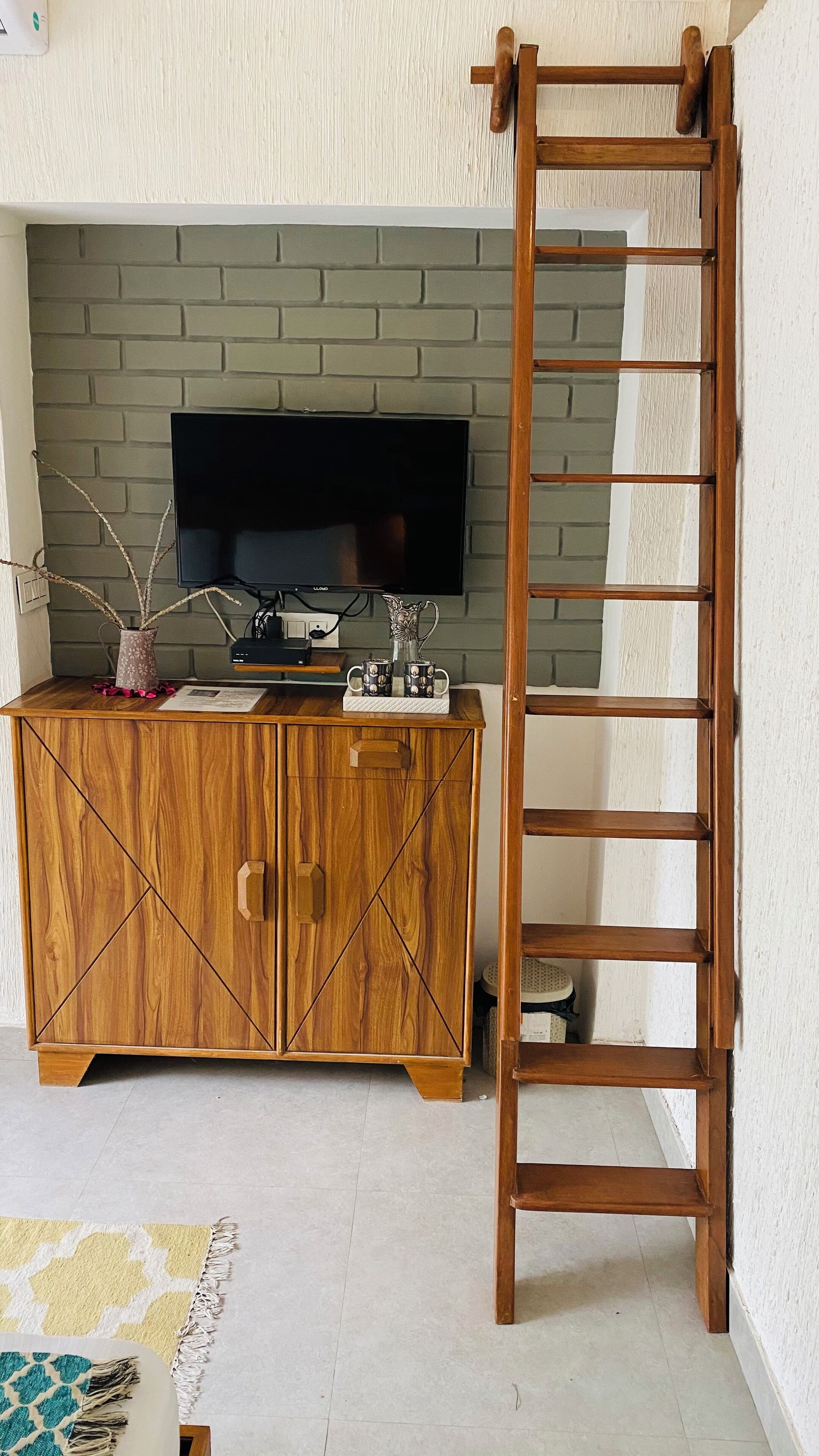 A wooden cabinet with a television, a ladder, and decorative items.