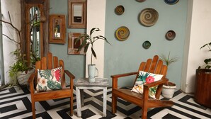 Una habitación con dos sillas de madera, una mesita y una pared decorada con platos redondos.