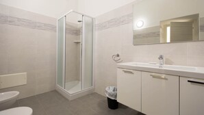 A bathroom with a glass-enclosed shower, a toilet, and a sink with a mirror above it. - Three-room apartment with small balcony overlooking the alleyway (Alassio)