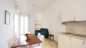 A modern kitchen with white cabinets, a wooden countertop, and a built-in stove. There is a dining table with chairs and a fruit bowl. - Three-room apartment with small balcony overlooking the alleyway (Alassio)