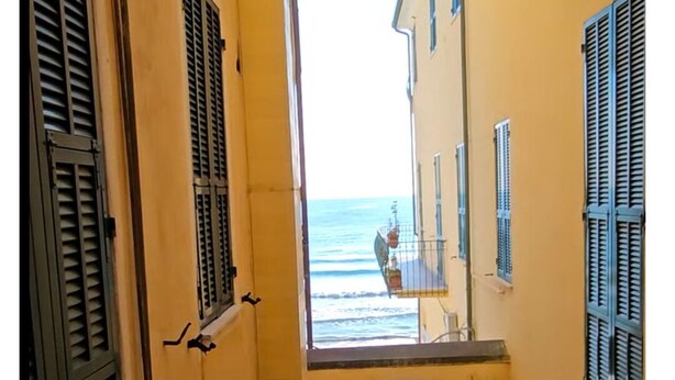 A narrow alleyway with yellow buildings and a view of the sea. - Three-room apartment with small balcony overlooking the alleyway (Alassio)