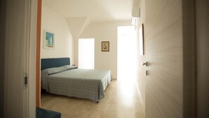 Ein Schlafzimmer mit Bett, Stuhl, einem Bild an der Wand und einer Tür zu einem anderen Raum.