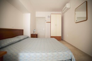 A bedroom with a bed, a wardrobe, a bedside table, and an air conditioning unit. - Beachfront apartment with a large balcony (Alassio)