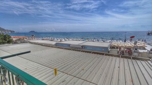 Eine Terrasse direkt am Strand mit Pool, Sonnenschirmen und Liegestühlen.
