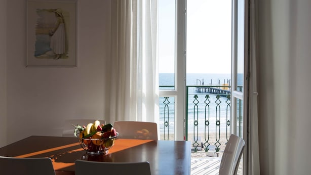 A dining area with a table, chairs, and a fruit bowl. A painting is on the wall. - Three-room seafront apartment with balcony (Alassio)