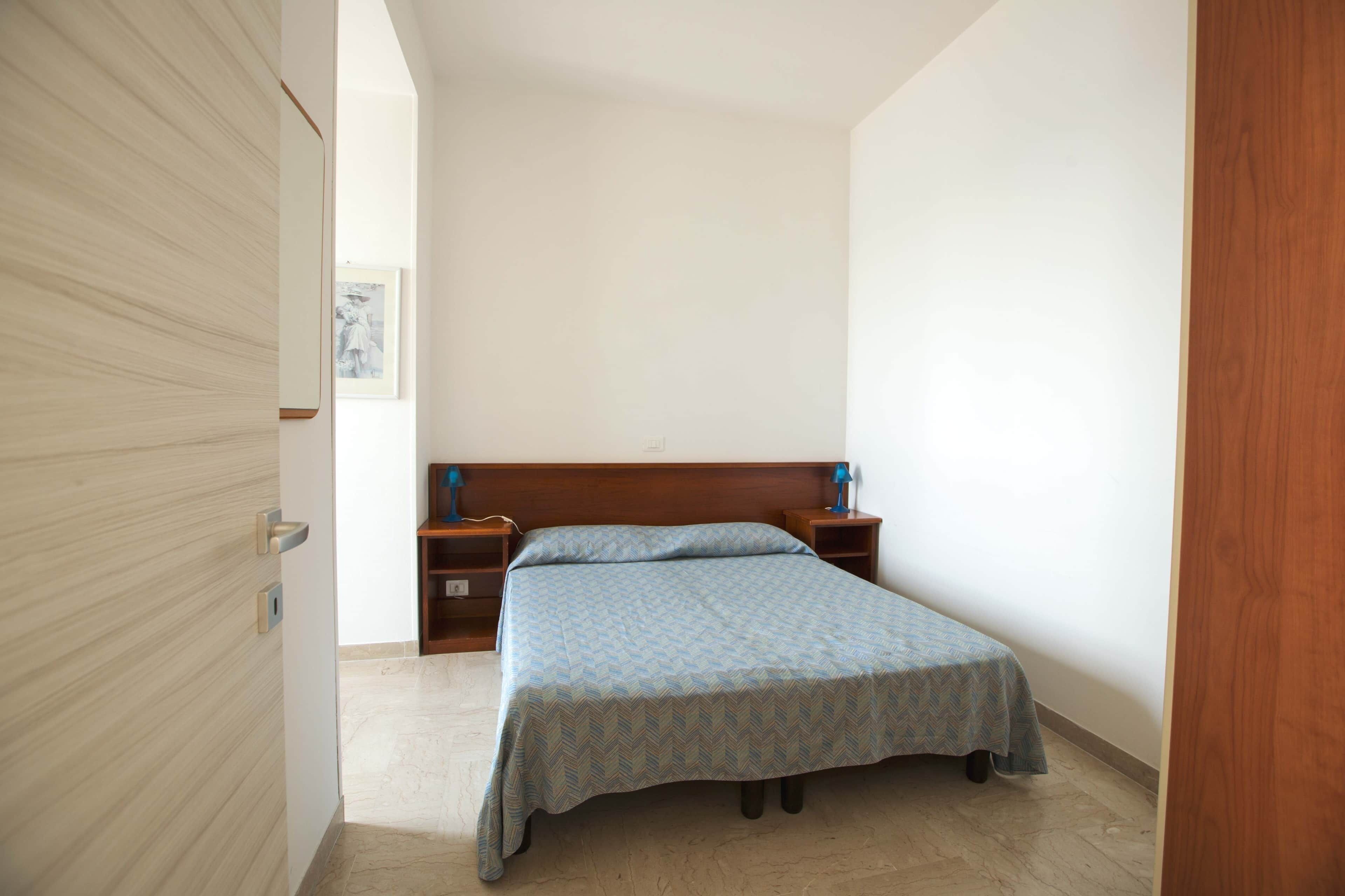 A bedroom with a bed, wooden headboard, bedside tables, and a nightstand.