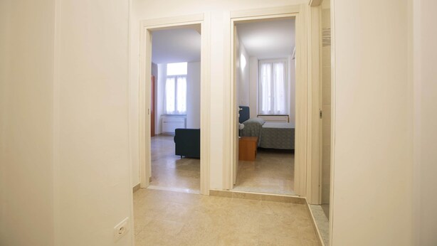 Un passadís amb un llit, una cadira i una taula petita a una habitació.