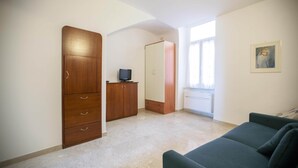 Una habitació amb un sofà verd, un armari de fusta i una televisió sobre una taula petita.