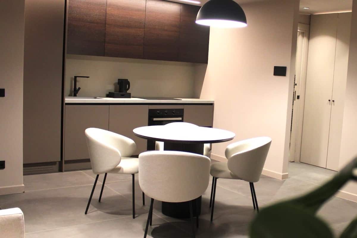 Een moderne keuken met een ronde eettafel en vier stoelen, een koffieapparaat en een hanglamp.