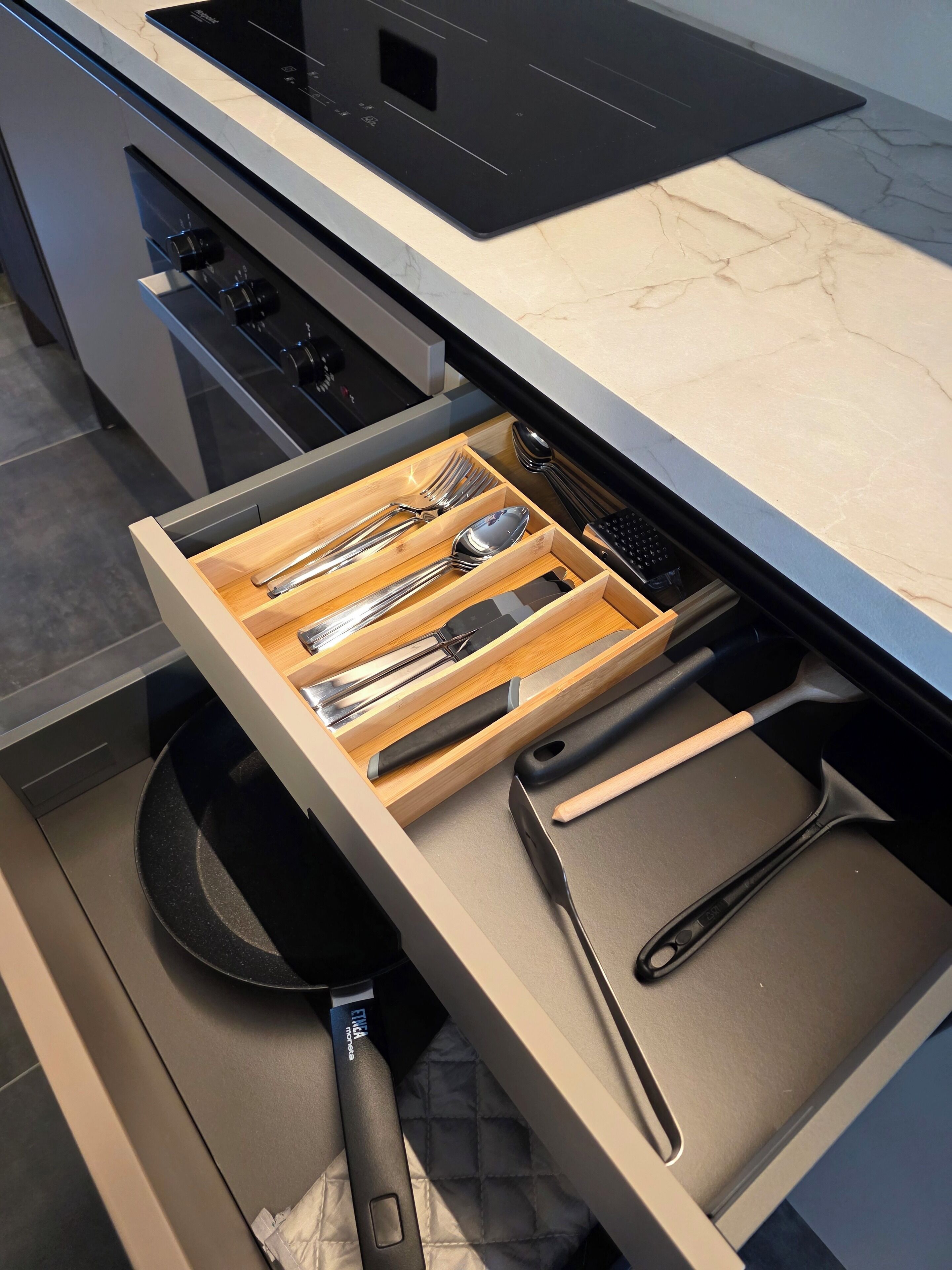 A kitchen drawer with utensils and cookware.
