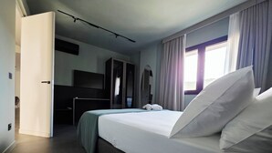 Une chambre d’hôtel moderne équipée d’un grand lit, d’une armoire, d’un bureau et d’un miroir.