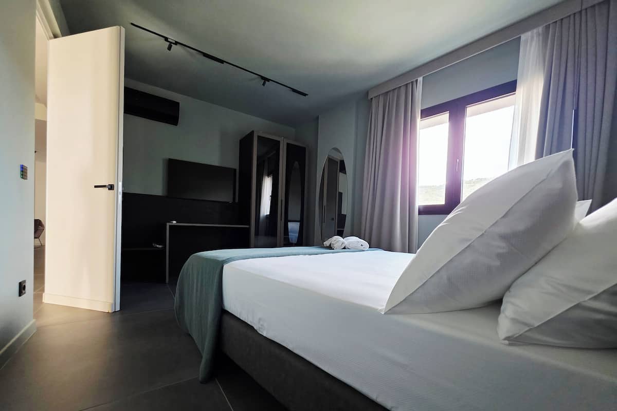 Een moderne hotelkamer met een groot bed, een kledingkast, een bureau en een spiegel.