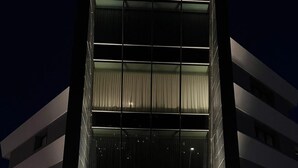 Un bâtiment moderne doté d’une façade en verre, d’une entrée bien visible et d’une enseigne sur laquelle on peut lire « PHISIA LIVING ».