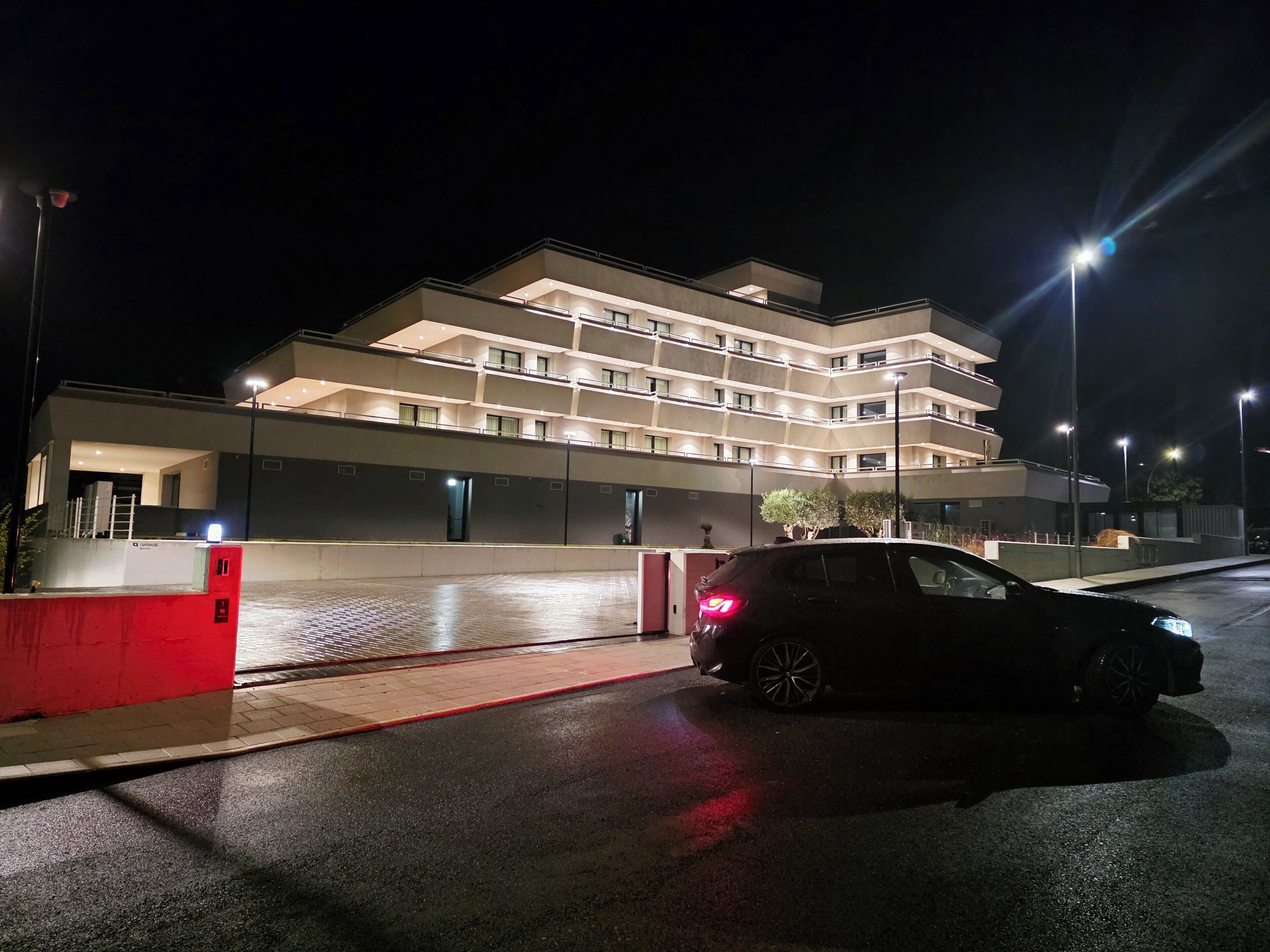 A multi-story hotel with a modern design, featuring a spacious entrance and a parking area.