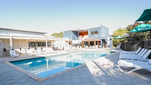 A swimming pool with lounge chairs and umbrellas, surrounded by buildings with a modern design. - "Serenity & Sea", Pool, Wi-Fi, Internet, Netfilix/Stan, 500m to Beach, Parking (Preston Beach)