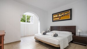 A bedroom with a bed, a painting, a window, and a lamp. - Miramar Apartment with sea views (Alcúdia)