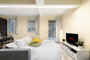 A modern hotel room with a bed, a TV, a dining area, and a balcony with curtains. - [Two-room Central] Outdoor Space - Station 5' (Bergamo)