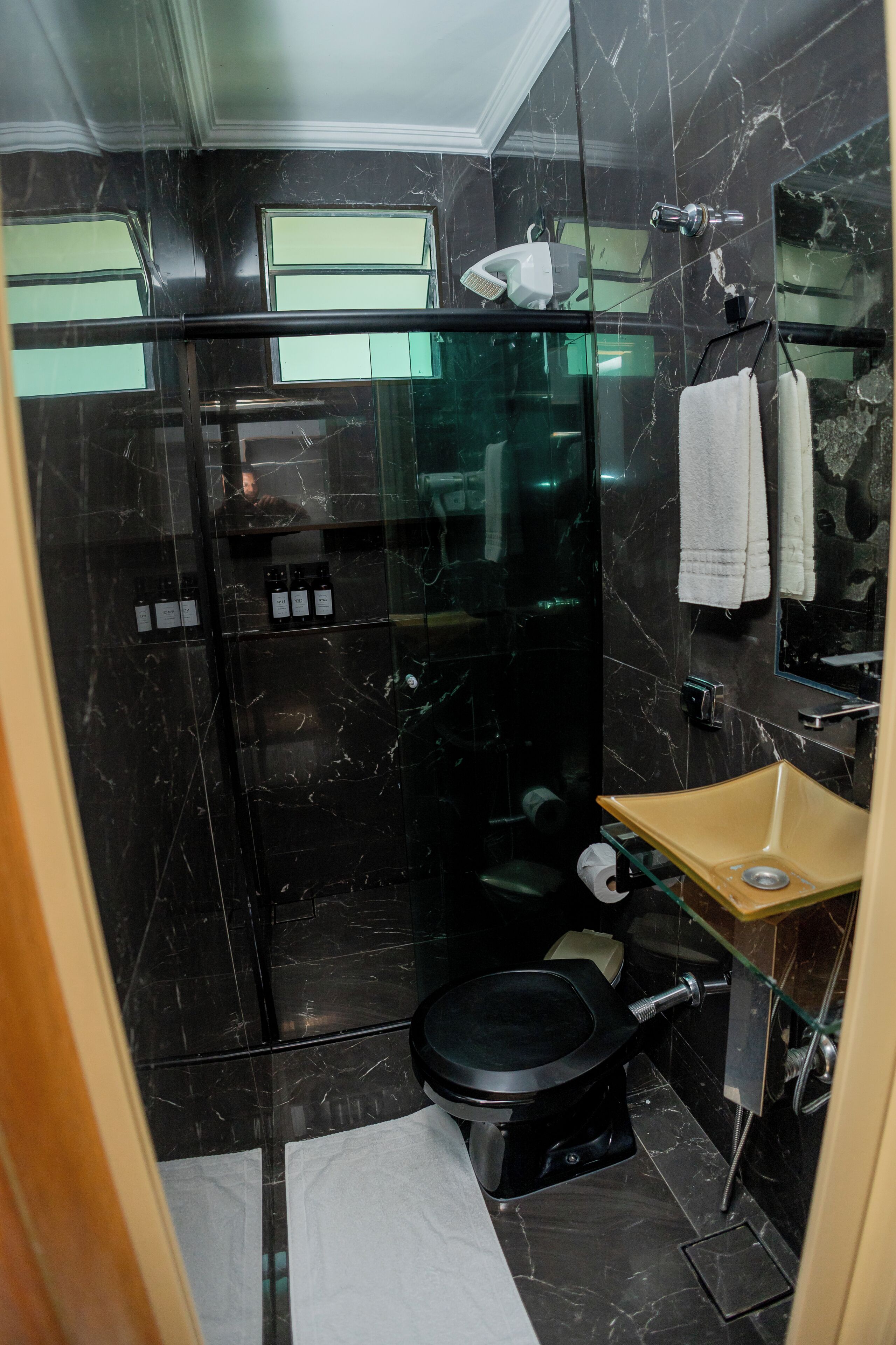 A modern bathroom with a glass-enclosed shower, a toilet, and a sink with a mirror.