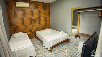 A small, clean room with two beds, a mirror, and a TV.