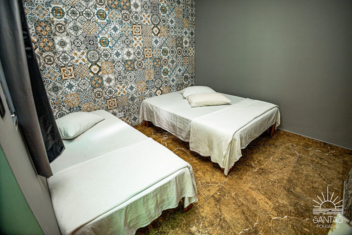 A room with two beds, a patterned tile wall, and a marble floor.