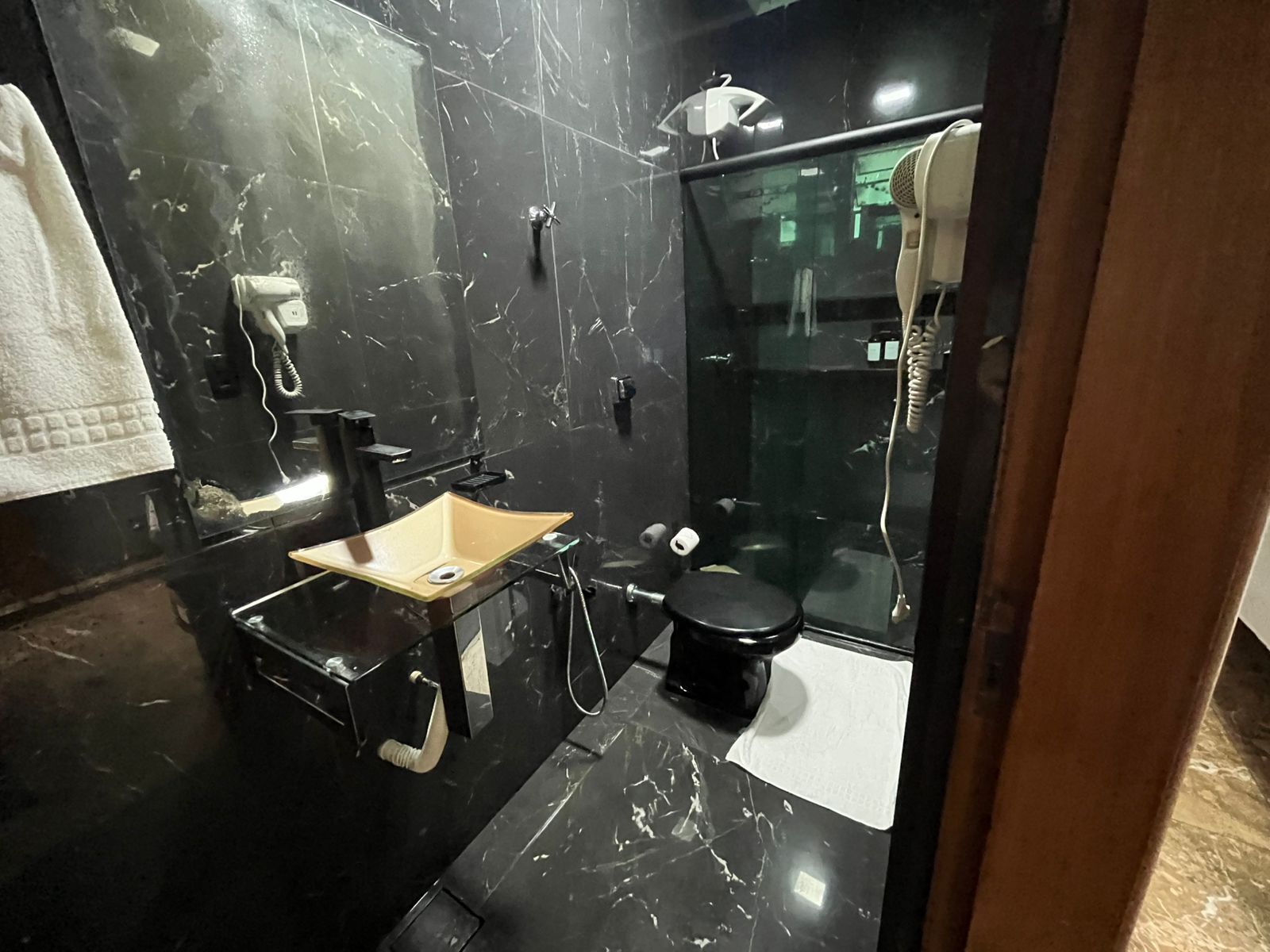 A bathroom with a black marble sink, a toilet, and a shower area.