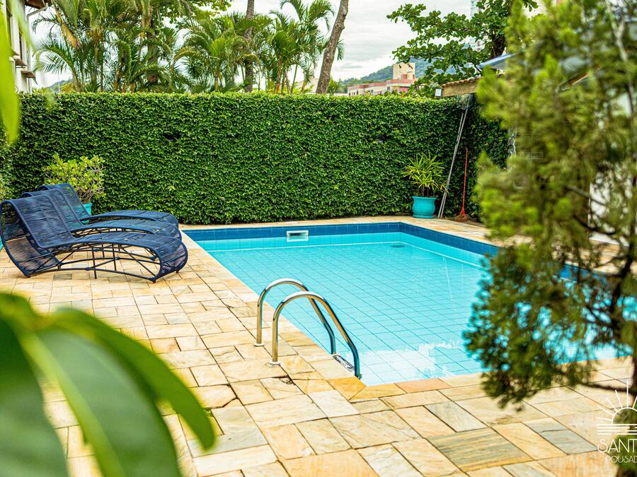 A swimming pool with a tiled edge, a metal ladder, and a blue lounge chair.