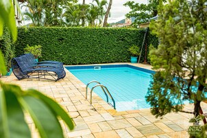 Una piscina al aire libre, sillones reclinables de piscina