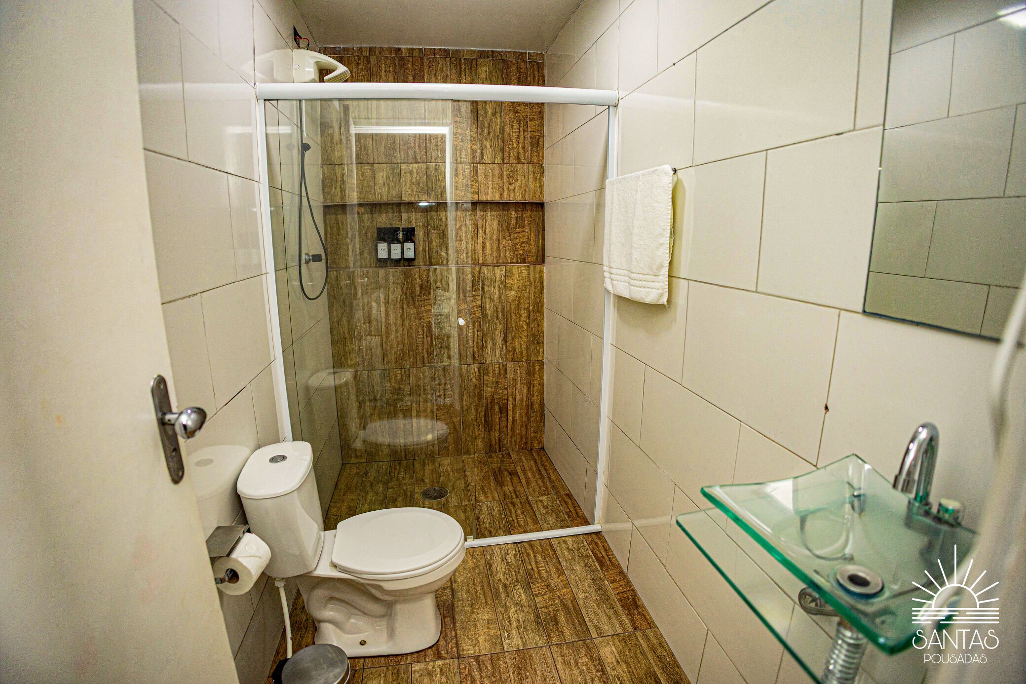 A bathroom with a glass shower enclosure, a toilet, and a glass sink.