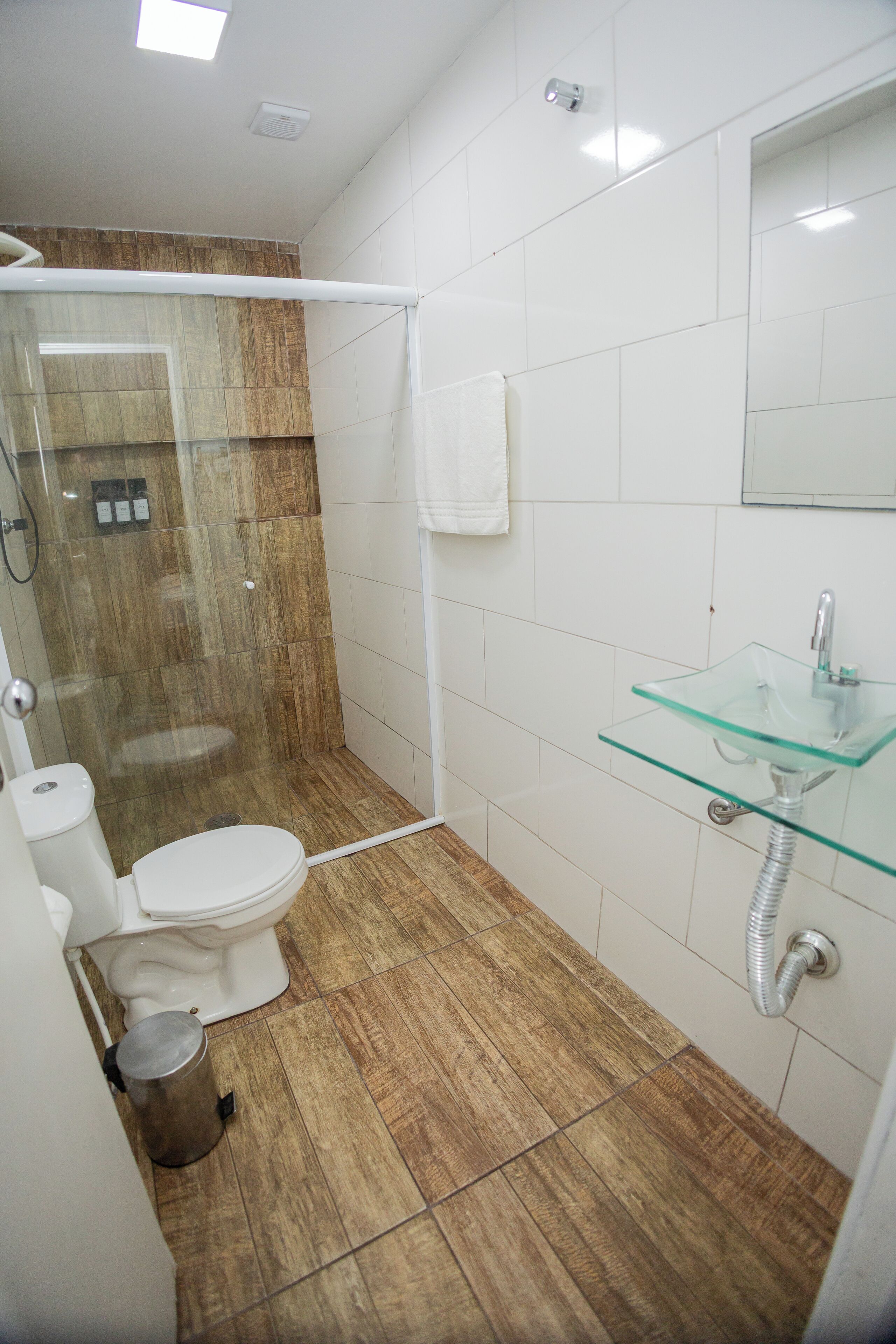 Ein Badezimmer mit einem Waschbecken aus Glas, einer Toilette und einer Duschkabine.