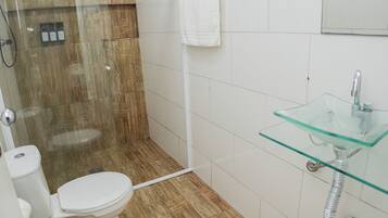 Ein Badezimmer mit einem Waschbecken aus Glas, einer Toilette und einer Duschkabine.