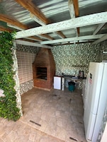 Una cocina con horno de ladrillo, paredes con azulejos, un refrigerador y suelo de baldosas.