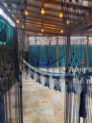 A hammock suspended between macramé ropes, a wooden ceiling, and a tiled floor. - Santa Cecília Pousada (Guarujá)