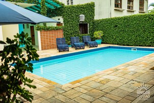 Una piscina al aire libre, sillones reclinables de piscina