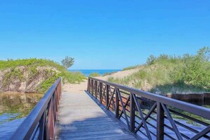 A wooden boardwalk leading to a beach with clear skies.