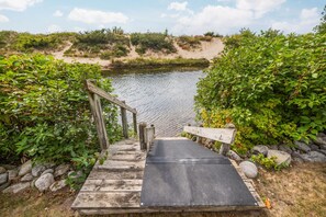 A wooden staircase leading to a dock over a calm body of water, surrounded by greenery.