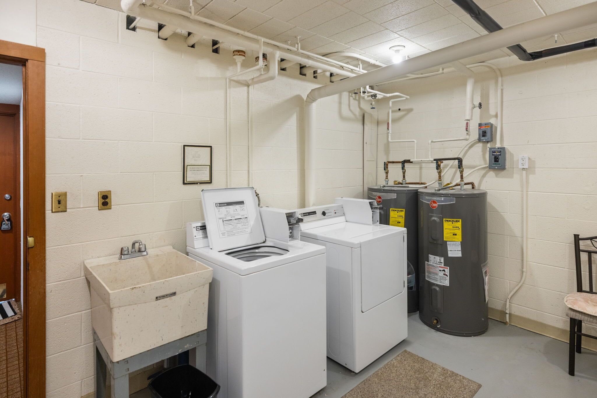 A laundry room with a washing machine, dryer, and two water heaters.