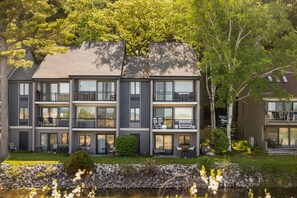 A modern multi-story residential building with balconies, large windows, and a landscaped garden.